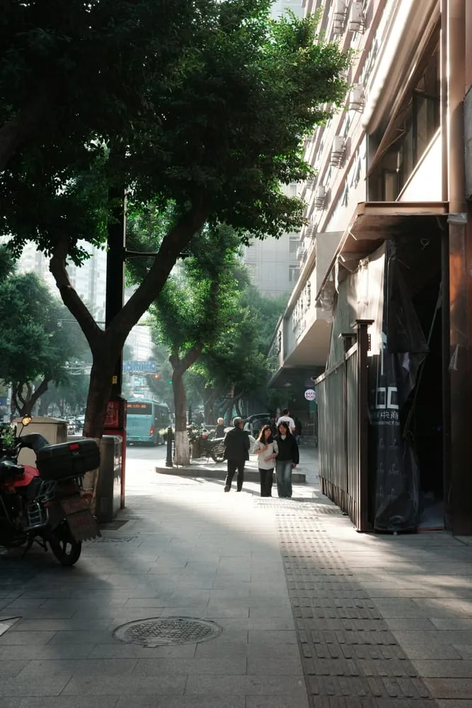 레이어드 구도 스트리트 사진 — 전경의 행인, 중경의 가게, 원경의 건물이 층을 이루는 거리 사진